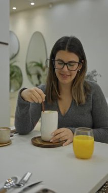 Modern lüks restoranlarda kahve içen bir kadın, parlak ışıklandırmalı, şık dekorlu ve rahat atmosferli, otururken içeceğini sessizce yudumlayan..