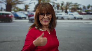 Gülümseyen son sınıf öğrencisi kadın, şehir dışında arabaların ve palmiye ağaçlarının arka planında mutluluk ve pozitiflik sergiliyor..