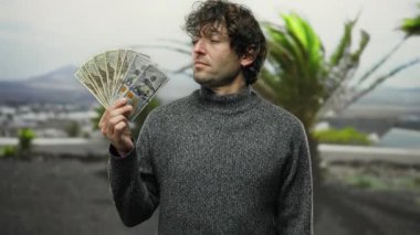 Amerikan dolarlarını elinde tutan İspanyol bir adam şehir sokaklarında zenginlik ve finansal başarı sergiliyor. Doğayla iç içe..