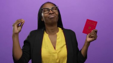 Kadın, elinde mor duvar arkasında Avusturya pasaportu tutarken duygularını ifade ediyor.