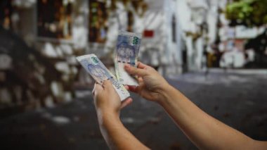 Güney Afrika paralarını elinde tutan bir adam, bir şehir caddesinde finans ve ekonomi sergiliyor, açık havada para değişimi yapan bir şehir ortamında..