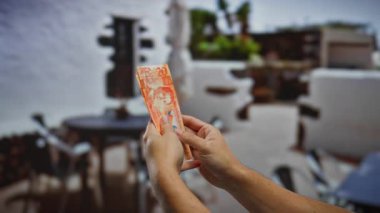 Güneşli bir açık havada Filipin pesolarını elinde tutan adamın elleri mali işlemleri ve yatırım olanaklarını gözler önüne seriyor..