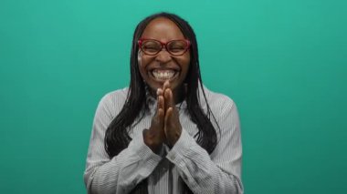 Canlı yeşil bir arka plana gülümseyen, gözlüklü, çizgili gömlekli, mutluluk ve enerjiyi ifade eden bir kadın..