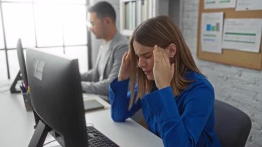 Bir kadın ofis ortamında iş stresi ve odaklanma gösteren kapalı alanda çalışan bir adamla bilgisayarın başında stres yapıyor..