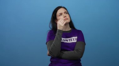 Gönüllü gömleğini mavi arka plana takan bir kadın, esmer kadın gönüllü ruhu ve gündelik kıyafetlerini sergileyerek derin düşüncelere daldı..