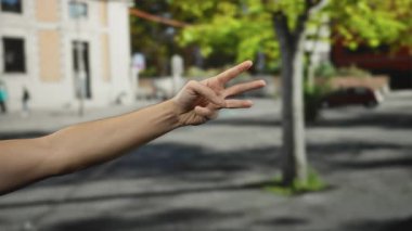 Şehir sokaklarında el kol hareketi yapan, parmaklarıyla üçe beş arası sayan ve onaylama ve pozitifliği vurgulayan bir adam..
