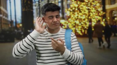 Genç adam, şehir sokaklarının ışıklarıyla dolu bir arka planda ilginç bir ifadeyi ve gece ortamında sıradan bir modayı vurguluyor..