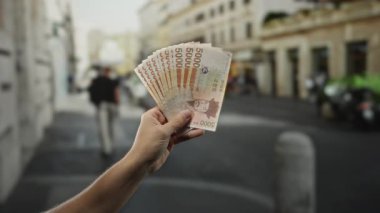 Güney Kore 'yi elinde tutan adam, şehir merkezinin arka planında mali büyüme ve dış yatırımı temsil eden bulanık arkaplanlı banknotlar kazandı..