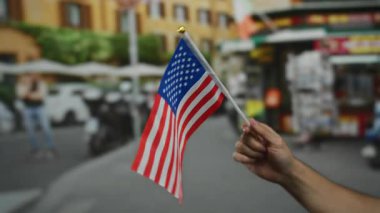 Erkek el ele tutuşması, Amerika 'nın şehir ortamındaki vatanseverliğini sembolize eden bulanık bir geçmişe sahip şehir sokaklarında bayrak sallıyor..