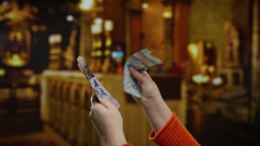 Kanadalı bir kadın kilisenin içinde sıcak ışıklandırmalı banknotlar sayarak sakin bir iş ortamı yaratıyor..