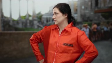 Hapishane tulumu giyen kadın, arka planda turistlerle birlikte Roma harabelerinin yakınlarında şaşkın şaşkın geziyor..