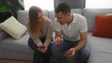 Oturma odasında kadın ve erkek akıllı telefonlar ve kredi kartlarıyla finansmanı tartışıyor, kanepede oturuyor, rahat bir ev ortamı öneriyor..