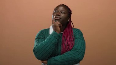 El pençe divan duran kadın tenha kahverengi arka planda düşünceli bir ifadeyle derin düşüncelere dalmış..