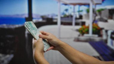 Bulanık bir şehir caddesi boyunca Brezilya banknotları tutan adam halka açık bir alanda para işleme vurguluyor..