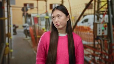 Şantiyede uzun saçlı pembe kazak giyen bir kadın hayal kırıklığına uğramış görünüyor. Şehir ortamında hayal kırıklığı ya da karmaşa olduğunu söylüyor..