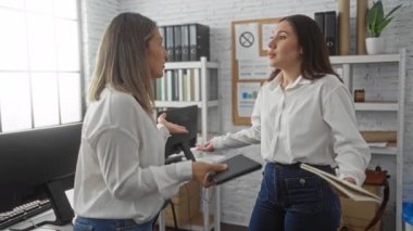 Ofis ortamında iş stratejisini tartışan kadınlar, teknoloji ve yaratıcı çalışma alanı unsurları arasında ortaklık ve işbirliğini ön plana çıkarıyor.