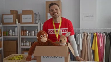 Gönüllü iş ve toplum desteğini vurgulayarak bağış kutusuyla hayır kurumunun içinde kalp hareketi yapan genç adam.