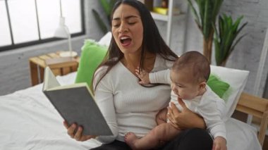 Yatak odasında kızıyla kitap okuyan bir kadın sevgi ve beraberlik gösteriyor..