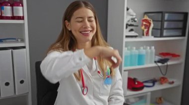 Üniformalı, beyaz bir kadın, poliklinikte gülüp el sallıyor.