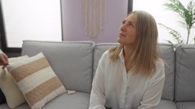 Anne ve kızı sıcak bir oturma odasında sevgi dolu bir şekilde kucaklaşıyorlar. İki kadın arasındaki samimiyet ve aile bağını sergiliyorlar..