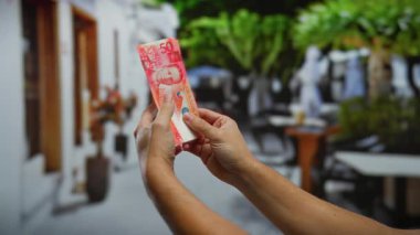 Sokaklarda Filipinli pesoları tutan adam, açık hava ortamında renkli banknotlar sergiliyor, yatırımları ve finansal temaları ön plana çıkarıyor..