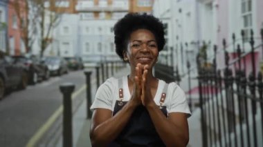 Şehir caddesinde önlükle gülümseyen bir kadın canlı bir mimarinin ortasında pozitif kentsel yaşam tarzı sergiliyor..