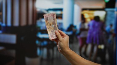 Kirli para birimlerini kapalı bir kafede tutmak, mali işlemleri ve iş kavramlarını gösteren bulanık bir arka plan..