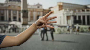 Aziz Peter Meydanı, Vatikan 'da bir adamın eli kolu kaldırılmış ve parmaklarını hareketli meydanın ortasında gösteriyor..