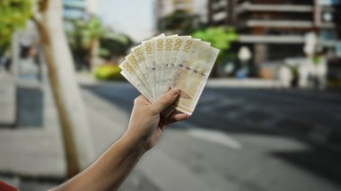 Bir şehir caddesinde Danimarka kronu banknotları tutan bir adam, açık şehir ekonomisinin ve Danimarka 'daki finansal faaliyetlerin özünü yakalıyor..