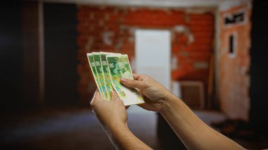 İsrail şekellerini inşaat halindeki şehir evinde tutan adam, kapalı bir şehir ortamında emlak gelişimine yatırım potansiyelini vurguluyor.