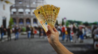 Roma Kolezyumu 'nun önünde el ele tutuşan Filipin pesoları, şehir ortamında finans ve turizm karışımı kavramları yakalamak..