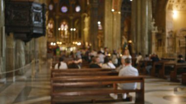 Kilisenin içi bulanık, insanlar sıralarda oturuyor, arka planda bokeh ışıkları olan, dağılmış dini bir ortam sergiliyorlar..
