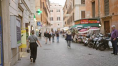 Roma 'da, dışarıdaki pazarlar ve eski binalarla çevrili kaldırım taşı caddesinde yürüyen insanların olduğu bulanık bir manzara..