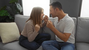 Erkek ve kadın oturma odasında neşeyle gülümsüyor, modern bir evde sevgi ve ilişkiyi tasvir ediyor, sıcak ve güzel bir çift anı yaratıyor..