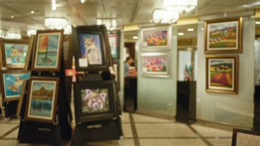 Bulanık sanat galerisi sahnesi. Odakları çözülmüş resimler ve açık arttırma atmosferini yansıtan ışık..