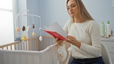 Yatak odasındaki rahat bir odada, beşiğin yanında kitap okuyan, meşgul ve düşünceli görünen, yumuşak ışıklandırmalı sıcak ve rahat bir ev atmosferi yaratan bir kadın..