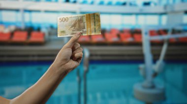 Norveç kronu taşıyan bir adam tatil köyü havuzunun yanında lüks bir su mekanında seyahat ve para çekme anı yakalıyor..