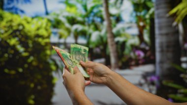 Güney Afrika Rand Rand 'ini canlı bir şehir parkında tutan adamın arka planda yemyeşil bir ortam var güneşli bir günde açık havada..