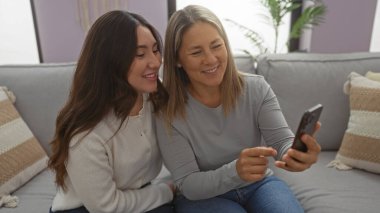 Anne ve kızı kapalı bir koltukta rahat bir şekilde oturup, bir telefona bakarak, sıcak bir yuva kurarak, sevgi ve bağ kurarak, şefkatli bir aile anını paylaşıyorlar..