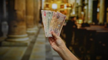 Arka planda kilise iç mimarisi, para, iş, banknotlar, dini bir ortamda finansal yönleri vurguluyor.
