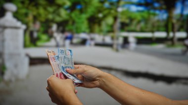 Şehir caddesinde Meksika pezosu tutan adam, kalabalık bir şehir ortamında iş ve yatırım taşıyor..