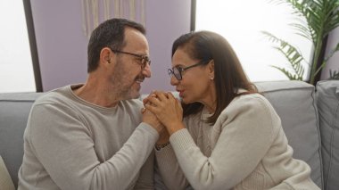 Orta yaşlı İspanyol çift evlerinde kanepede el ele tutuşup, evde sevgisini dile getiriyorlar..