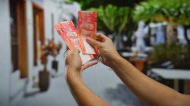 Yoğun bir şehir caddesinde Filipin pesolarını sayan bir adam, açık şehir ortamında yatırım, finans ve ticareti ön plana çıkarıyor..