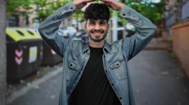 Kot ceketli gülümseyen adam, şehir sokaklarında neşeli pozlar veriyor..