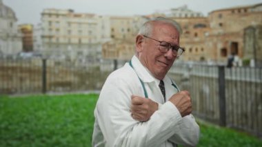 Doktor üniformalı kıdemli bir adam Roma harabelerinin yanında titriyor. Tarihi ve modern unsurları eşsiz bir sokak ortamında harmanlıyor..