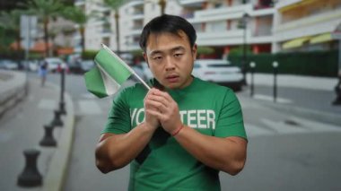 Elinde Nijerya bayrağı olan, yeşil gönüllü gömlekli arka planda bulanık şehir manzarası olan bir adam, çok kültürlü bir açık hava ortamını işaret ediyor..