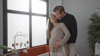 Hamile kadın ve erkek, sıcak, beklenti ve huzurlu bir atmosferle bir bebek odasında sevgiyle kucaklaşır..