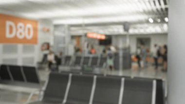 Havaalanının d80 kapısında bokeh etkisi ile bekleyen insanların bulanık fotoğrafı, modern terminal ortamında seyahat deneyimini vurguluyor.