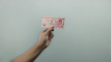 Profesyonel bir stüdyo ortamında finans, para ve ekonomi konularını vurgulayan Türk lira banknotunu beyaz arka planda tutan adam,.