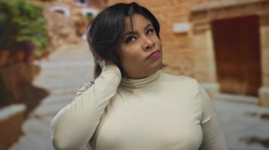 Şehir manzarasını düşünceli bir ifadeyle düşünen bir kadın. Canlı şehir caddesinde, sıcak açık havada, gündüzleri günlük giysiler giyerek..